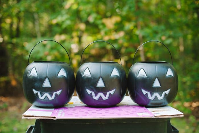 Three black plastic jack-a-lantern treat buckets for Halloween ready to be spray painted.