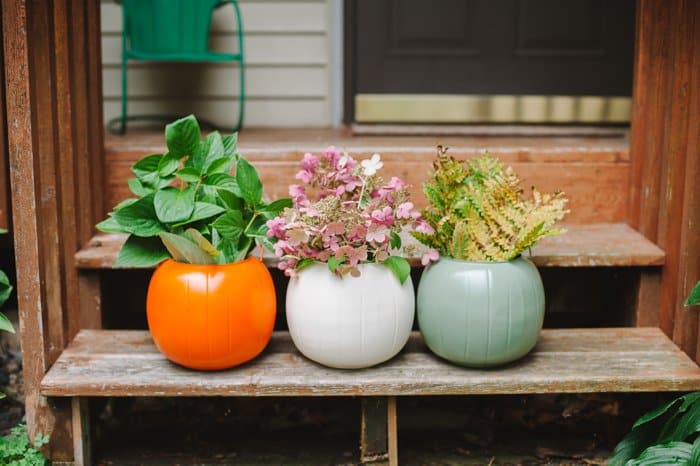 Spray painted pumpkin buckets filled with plant and flower clippings for Fall decorations on a front porch.