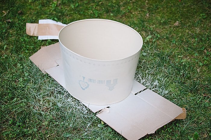 Spray paint an old lamp shade with primer to cover up any patterns, designs or stencils before wrapping in burlap