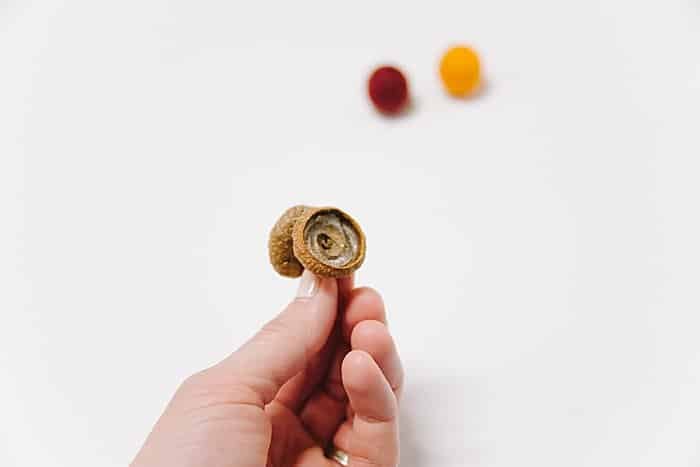 use hot glue to glue an acorn cap onto a felted ball