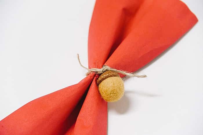 add acorns to twine to make napkin rings