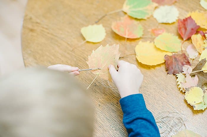 threading leaves onto twine is a fine motor activity for kids