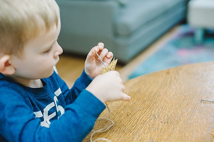 threading leaves onto a garland is a great preschool activity