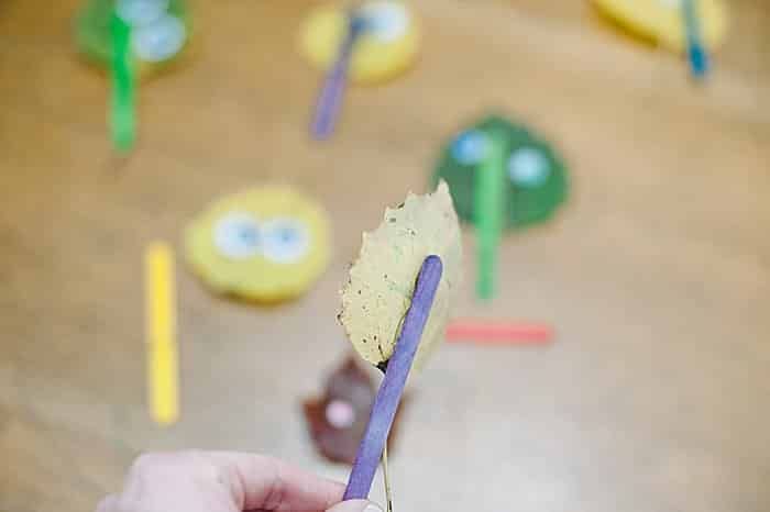 hot glue popsicle stick onto back of leaf puppet