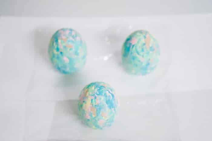 Pastel painted eggs drying upright on a white table.