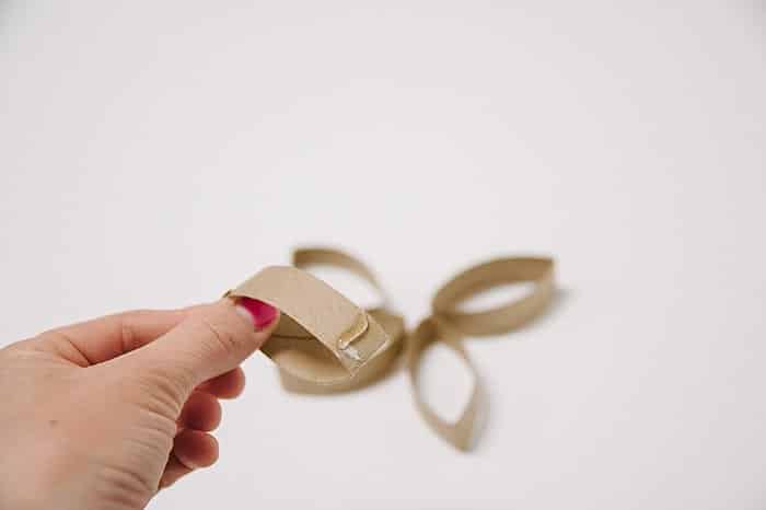 A hand holding a piece of cardboard with hot glue on it.