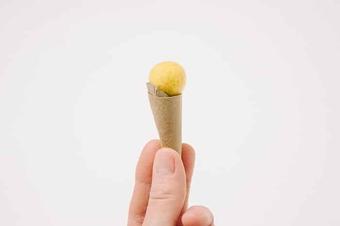 A handmade ice cream cone with a cardboard cone and a felt ball top. 