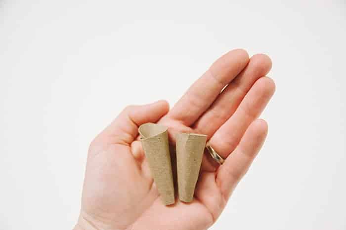 Two cardboard ice cream cones laying in the palm of a hand.