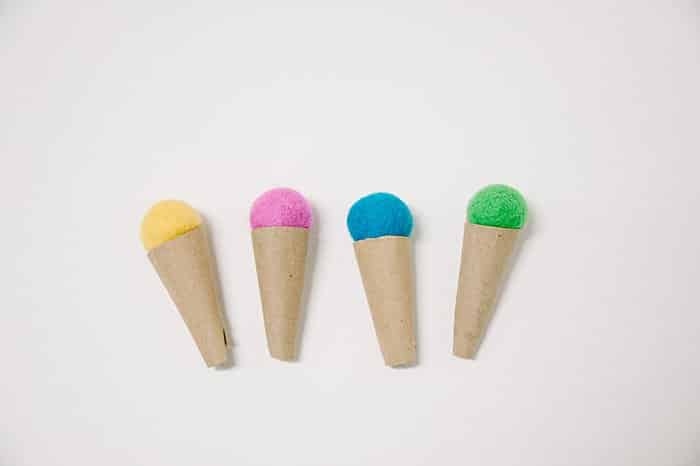 Four handmade ice cream cones with felt ball tops and cardboard cones.