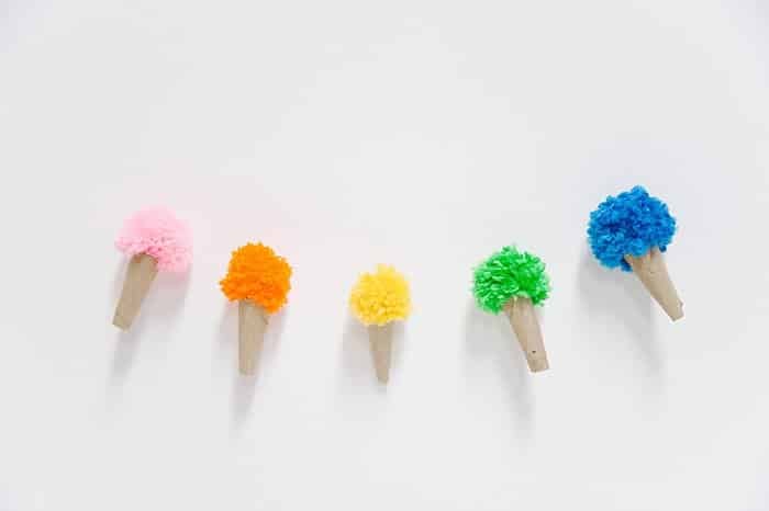 A garland made with homemade ice cream cones made with cardboard cones and yarn pompoms for ice cream.