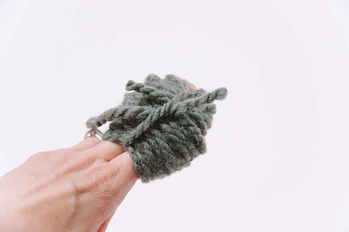 making a pom pom with thick chunky gray yarn