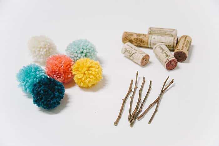 yarn pom poms, sticks and wine corks