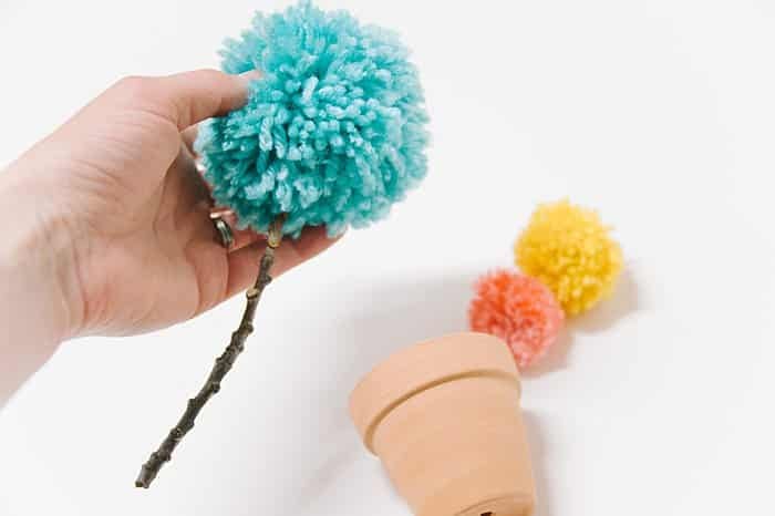 hot glue yarn pom pom to the end of stick stem