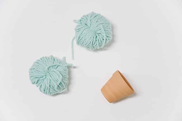 Two yarn pom poms to make DIY cactus plants.