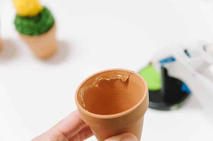 Hot glue yarn pom pom inside clay pot to make a cactus.