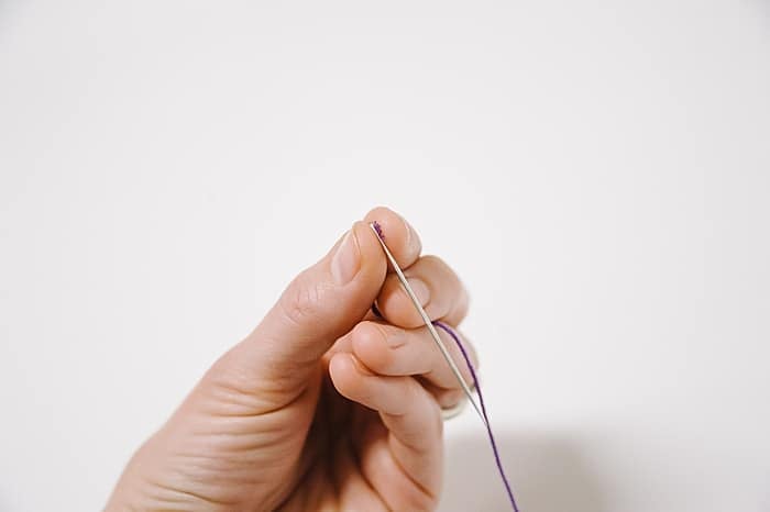 A hand threading a needle.