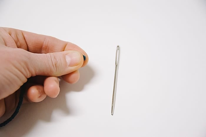 hold the thread right at the tip, between your thumb and pointer finger.