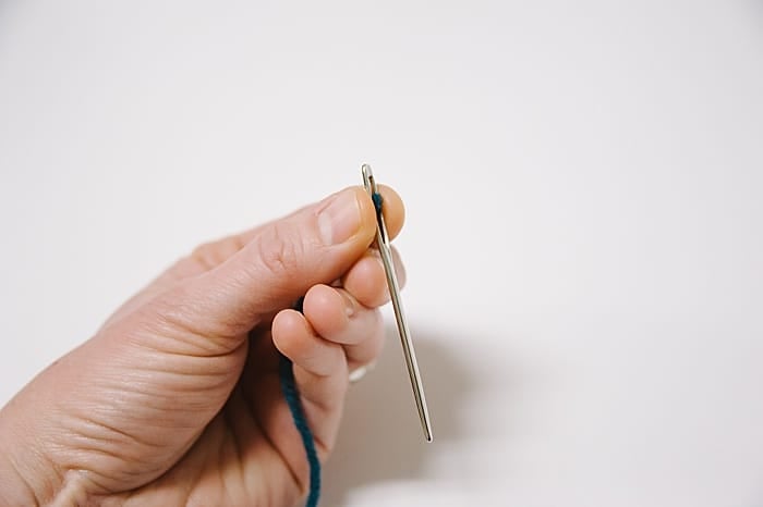 bring the needle to your yarn. push the needle onto the thread, and you'll see the thread peek it's way through