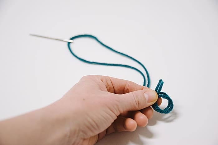 tie a knot in the end, using both tails of yarn