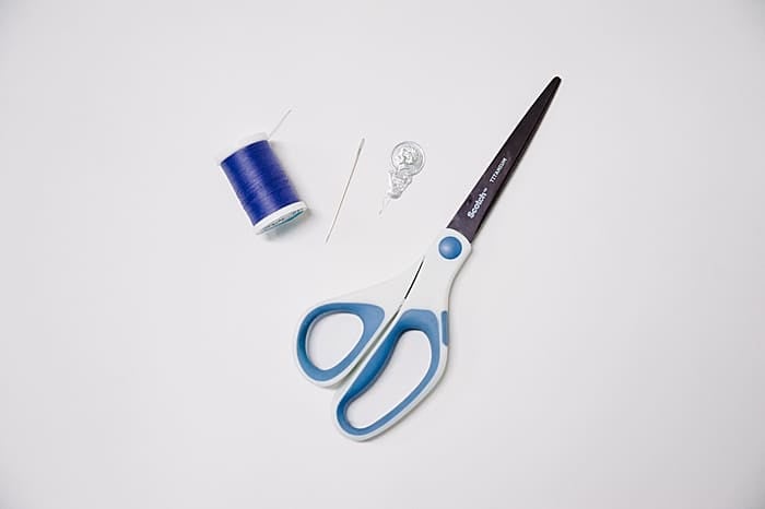 scissors, needle, thread, and a needle threader - supplies to use, to thread a needle with a threader.