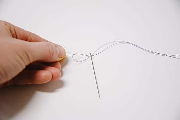 pull needle threader through eye of the needle (while pinching tightly to secure where the wire meets the needle threader) and keep pulling until thread loop comes through the eye of the needle