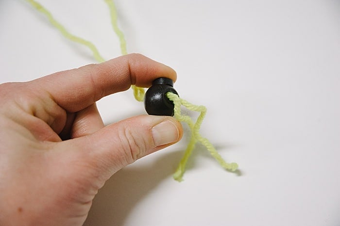 Squeeze the plunger on a fastener to open the hole to pass the strings from paper party had through.