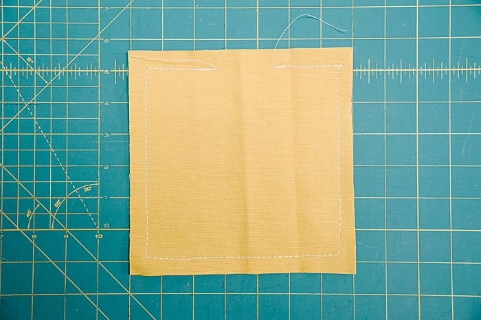 Yellow duck cloth square fabric with a ½ inch seam allowance sewn around it.