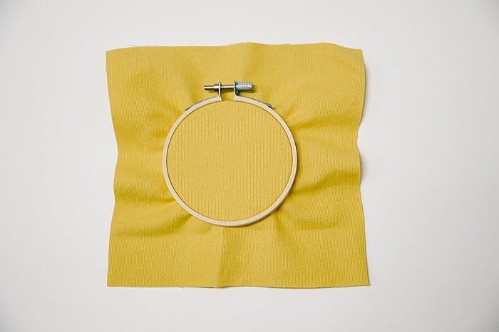 how to use an embroidery hoop by pushing outer hoop down over inner hoop and fabric to pull it tight