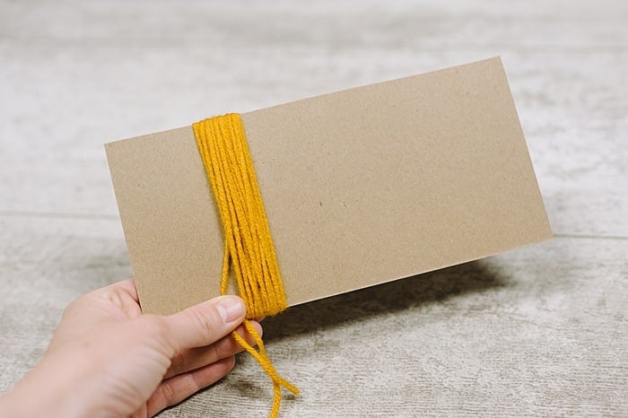Yarn wrapped around cardboard to make a yarn tassel.