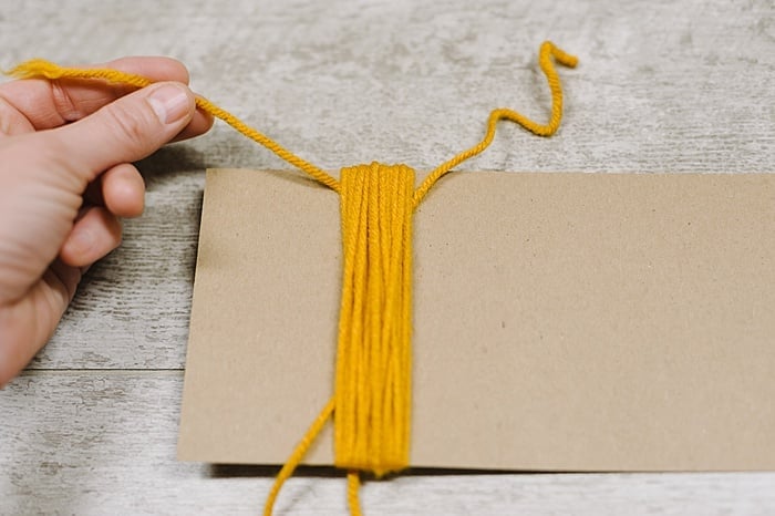 A yarn tassel being made using the cardboard method.