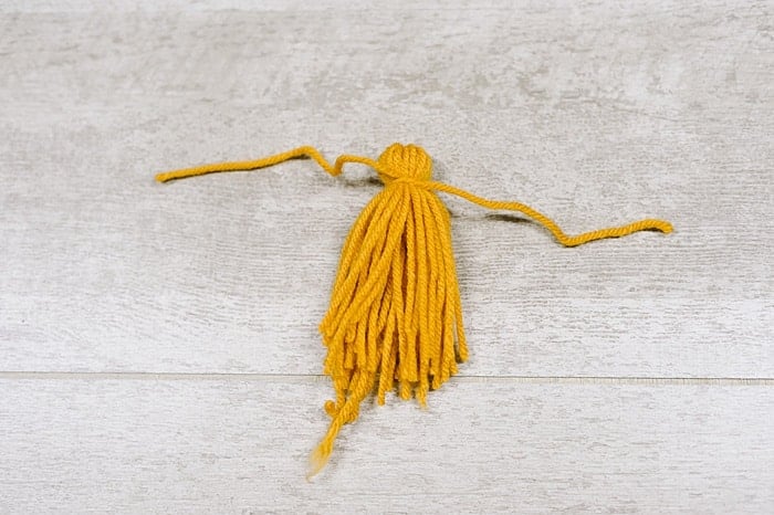 A yarn tassel being tied.