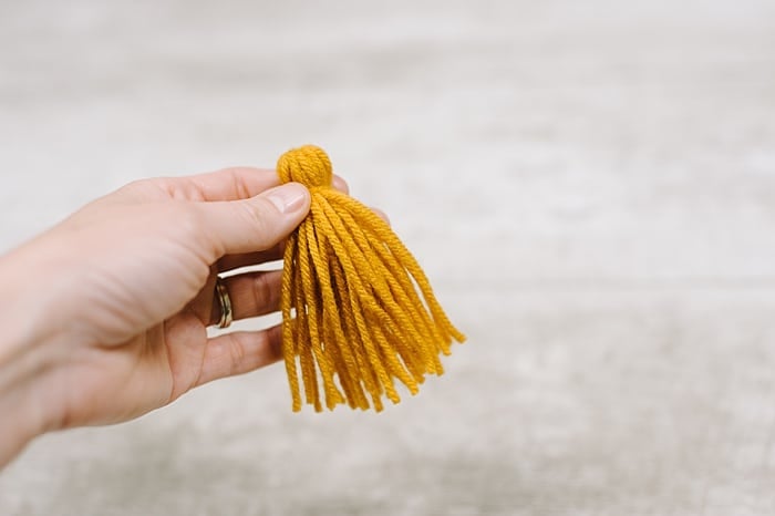 A yarn tassel held in a hand.