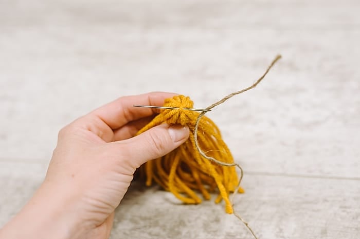 thread twine underneath the tie string at the top of the diy yarn tassel