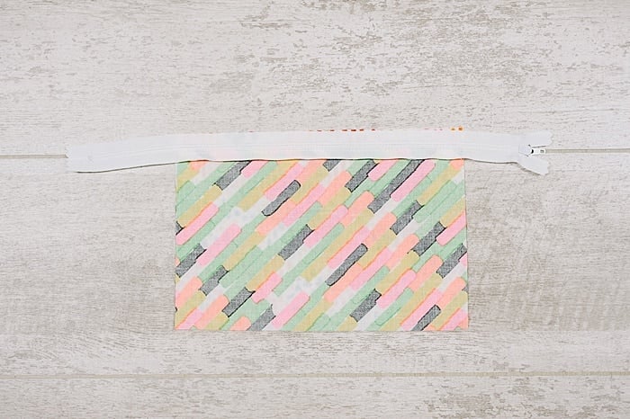 Fabric and zipper being sewn into a zipper pouch.