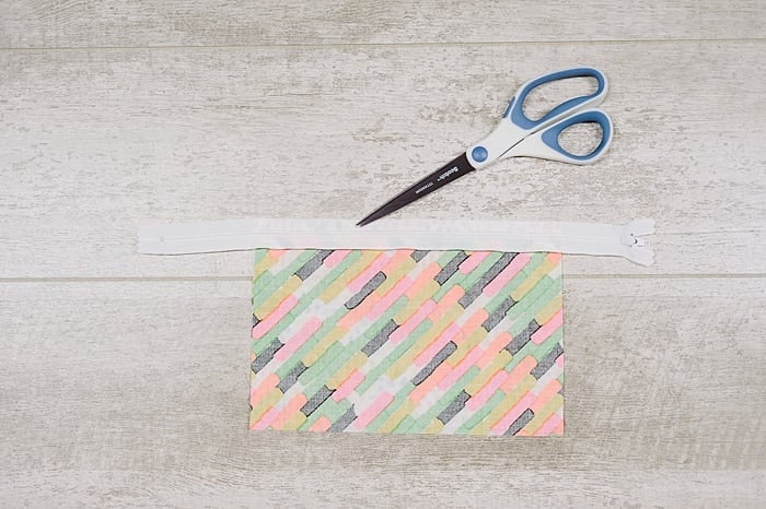Fabric and zipper being sewn into a zipper pouch.