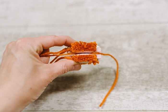 tie string tightly to secure middle of the pom-pom