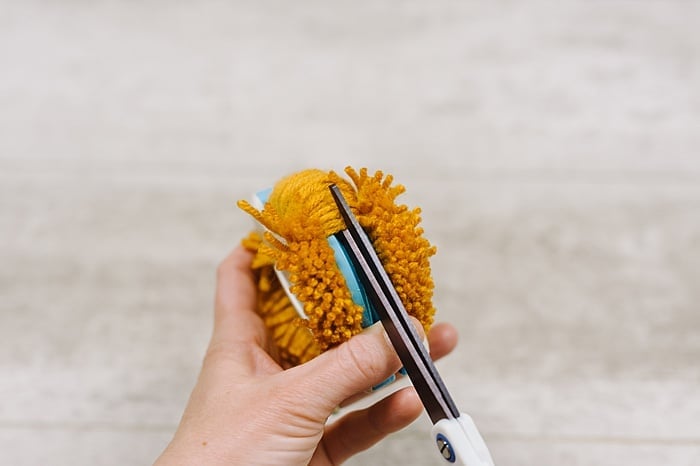 cut the bottom layer of yarn loops on the pompom maker