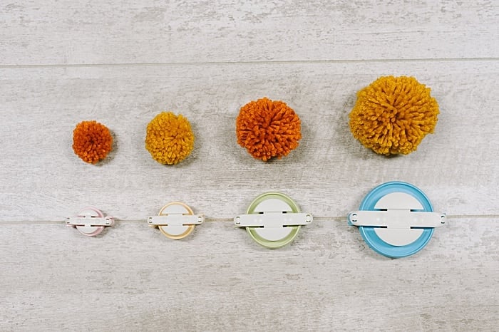 different sizes of pom poms made with pom pom makers