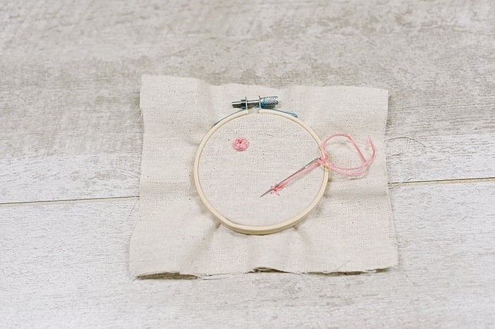 A woven wheel embroidery stitch on fabric in an embroidery hoop.