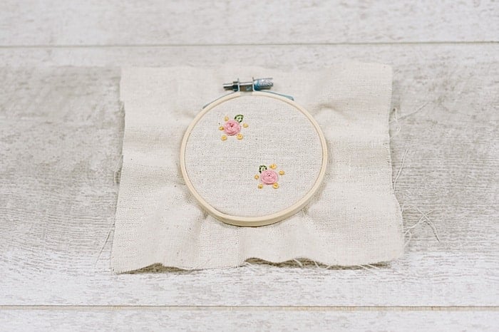 Embroidery for earrings on fabric inside an embroidery hoop.