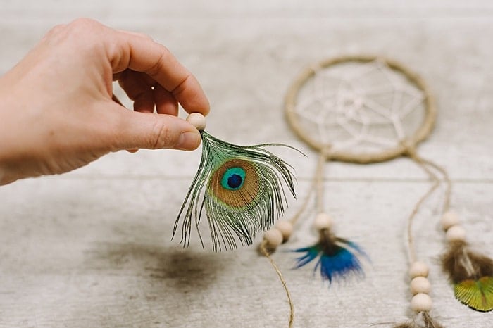 hot glue feather to the inside of a wooden bead first before adding