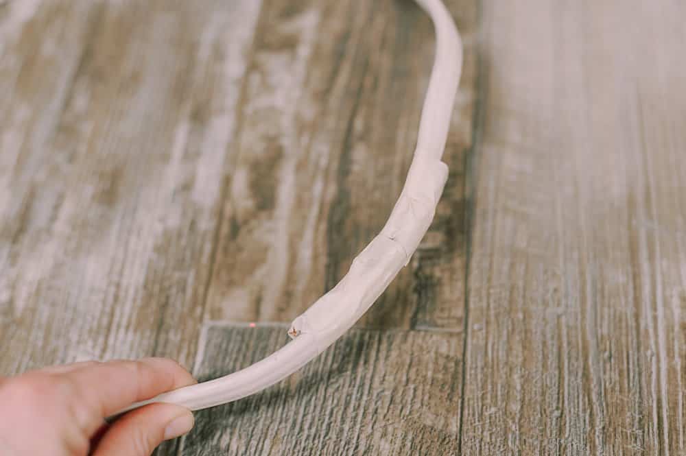 Old electrical wire formed into a circle, with the ends taped together with masking tape.