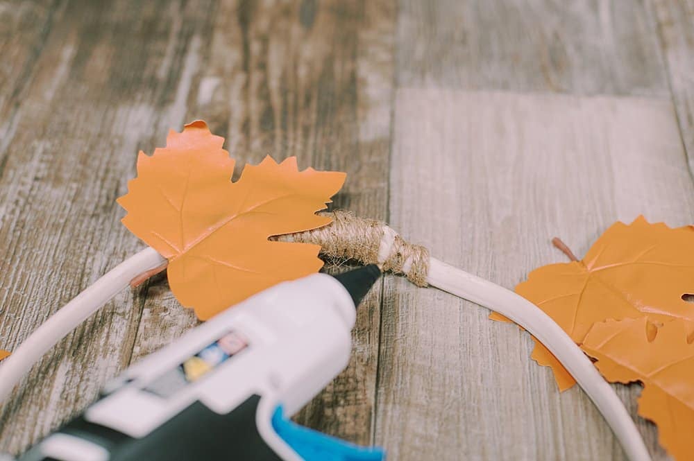 Hot glueing leather leaves onto a wire wreath form to make a wreath.