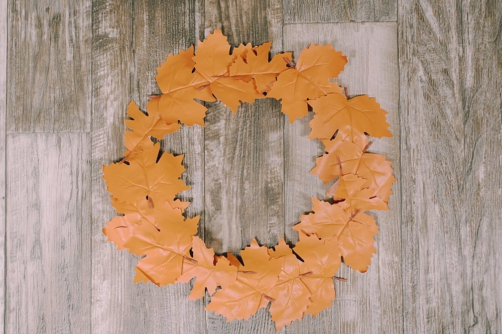 The front side of a fall wreath made of faux leather leaves.
