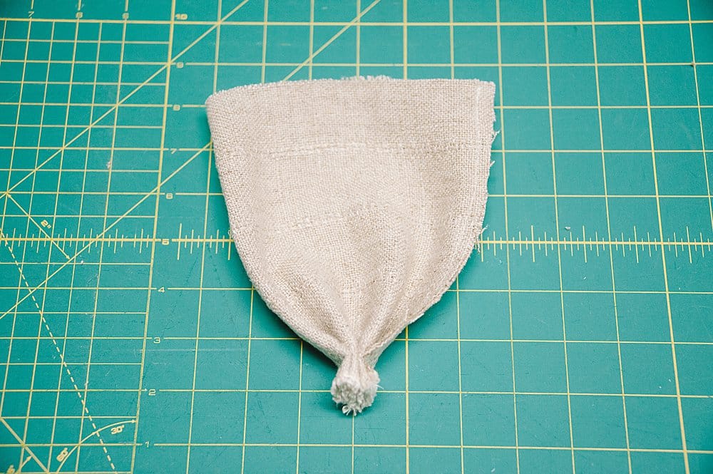 A small linen piece of fabric that is sewn along the bottom, laying on a sewing cutting mat.