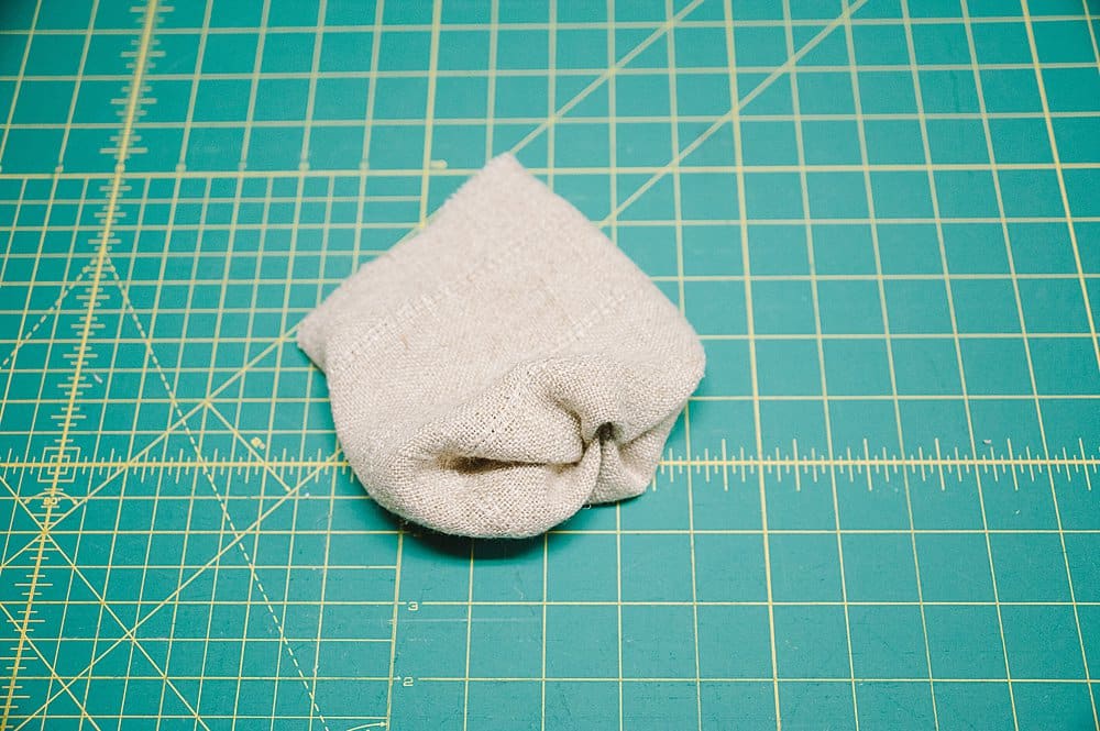 A small linen piece of fabric laying on a sewing cutting mat.