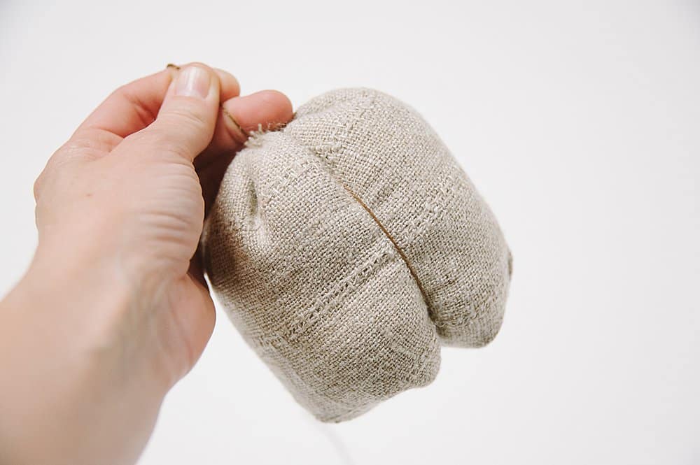 Sewing linen fabric to make a fabric pumpkin.