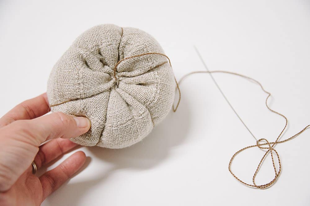 Sewing up linen fabric to make a fabric pumpkin.