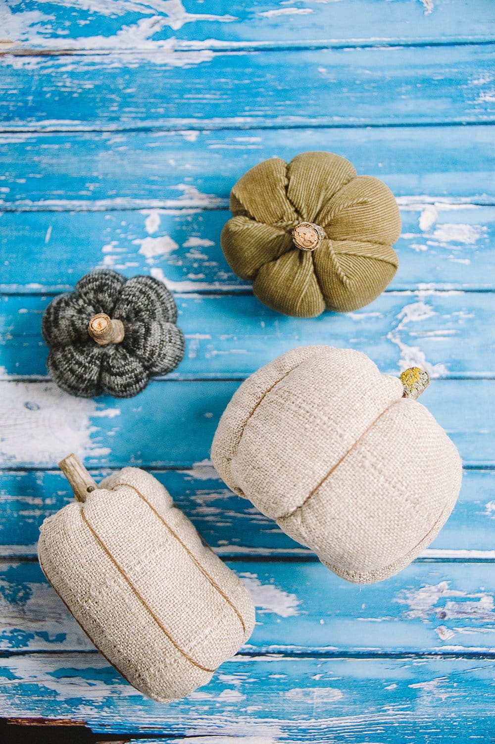 Homemade fabric pumpkins laying on a blue wooden background.