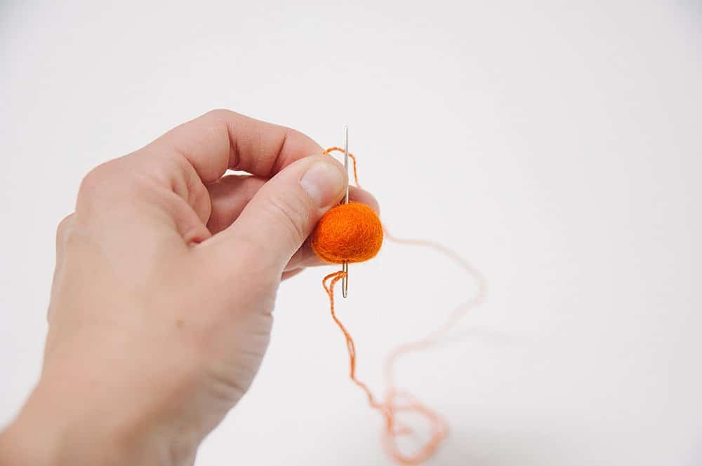 A needle, thread, and a felt ball.